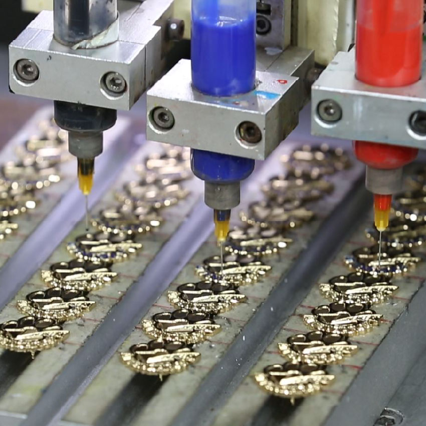 Automatic color filling machine in production process for a vibrant enamel metal bottle opener keychain Automatic color filling machine in production process for a vibrant enamel metal bottle opener keychain