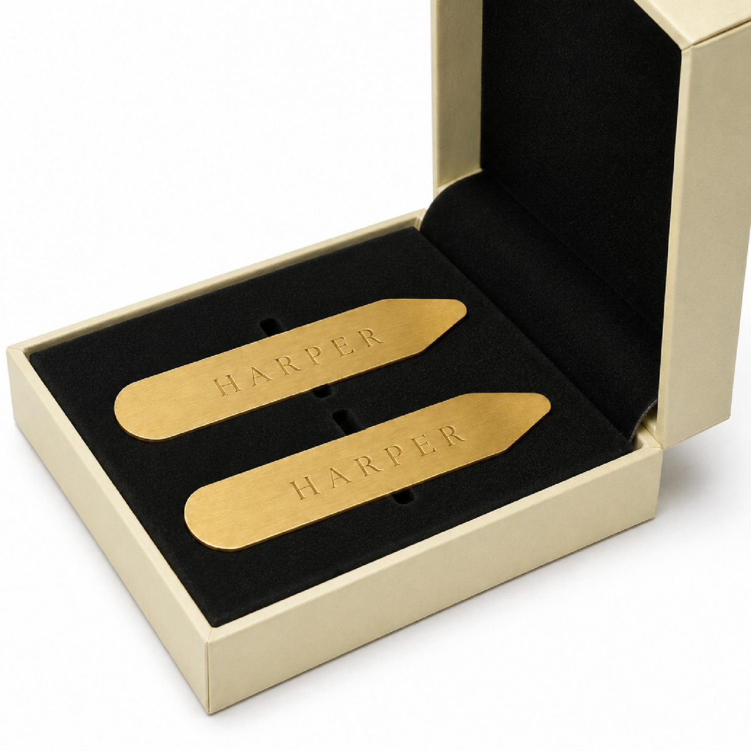 Two gold-tone brass collar stays arranged in a fitted presentation box