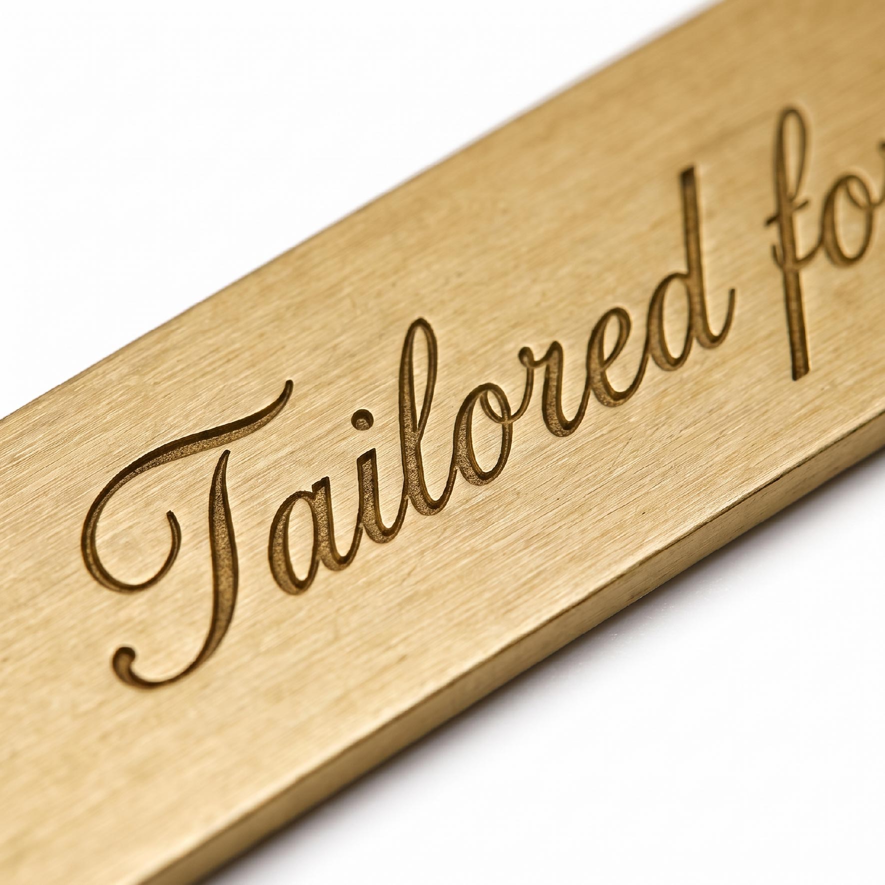 Recessed script lettering pressed into the surface of a brushed brass collar stay