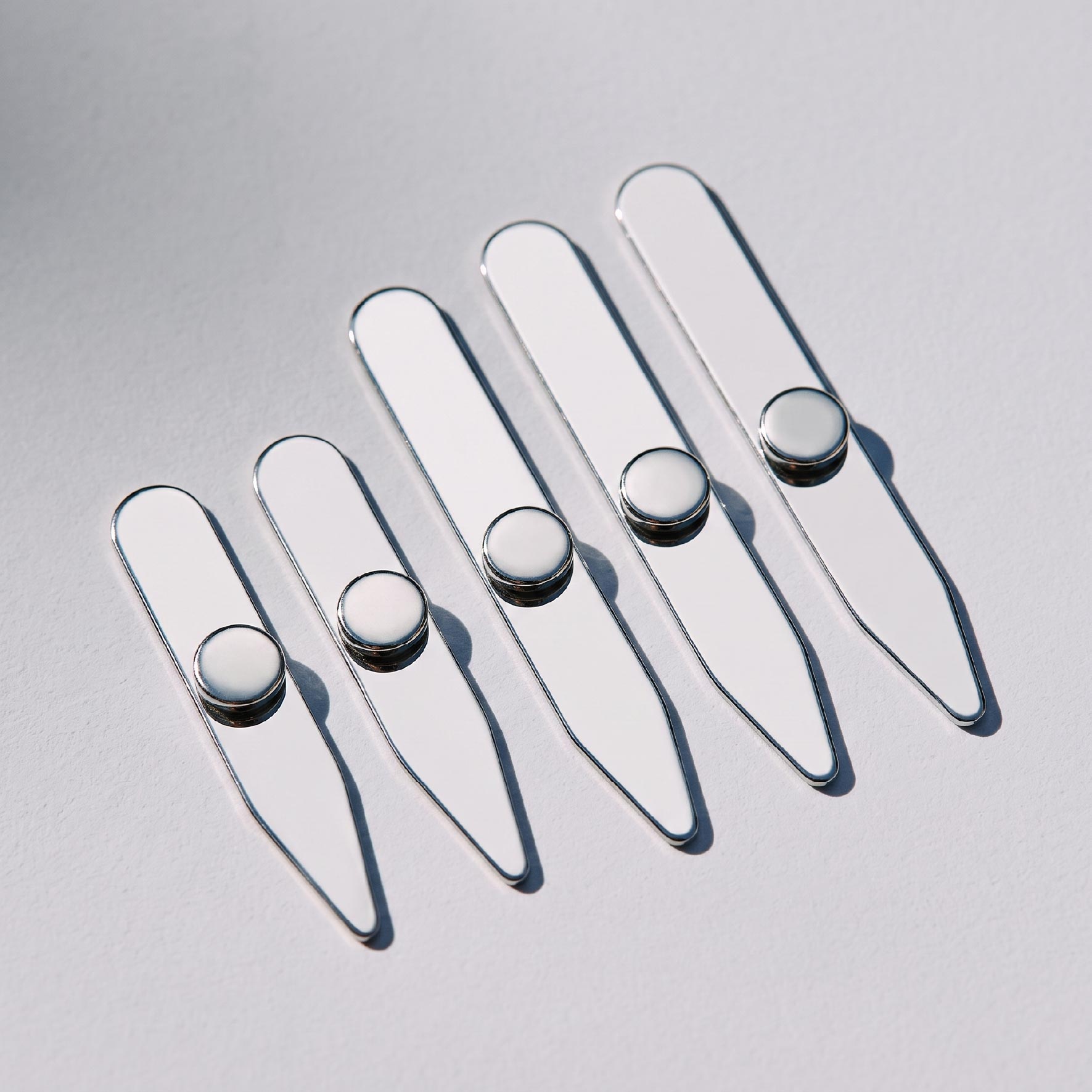 Five polished stainless steel collar stays displayed with round magnets for magnetic collar support
